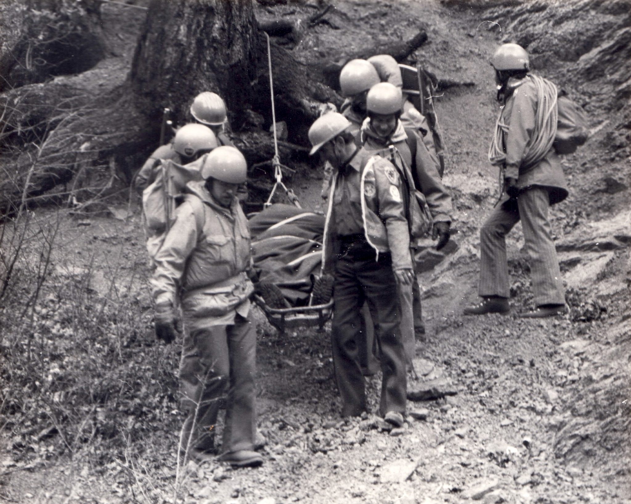 people walking with a litter on a rope